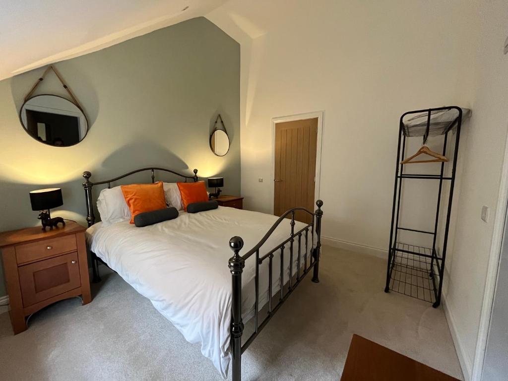 a bedroom with a bed with white sheets and orange pillows at Lime Tree Cottage in Tillingham