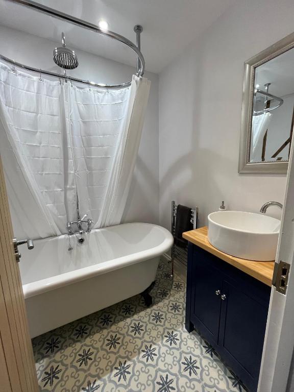 a bathroom with a tub and a sink at Lime Tree Cottage in Tillingham