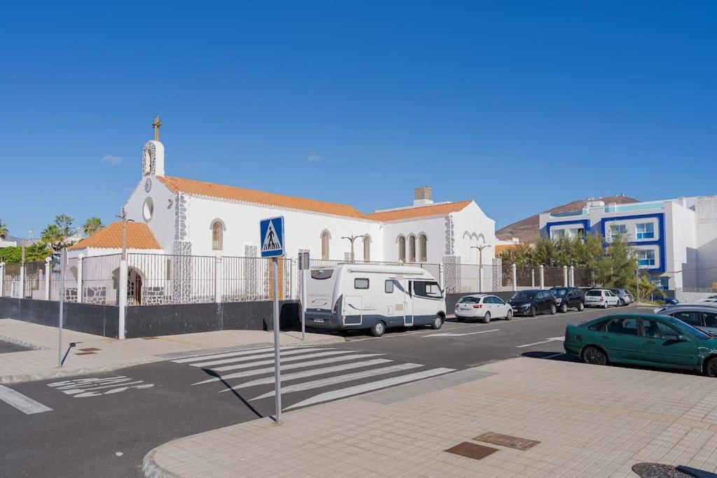 a white church with cars parked in a parking lot at Las Afortunadas , Playa Arinaga 1ºA in Arinaga