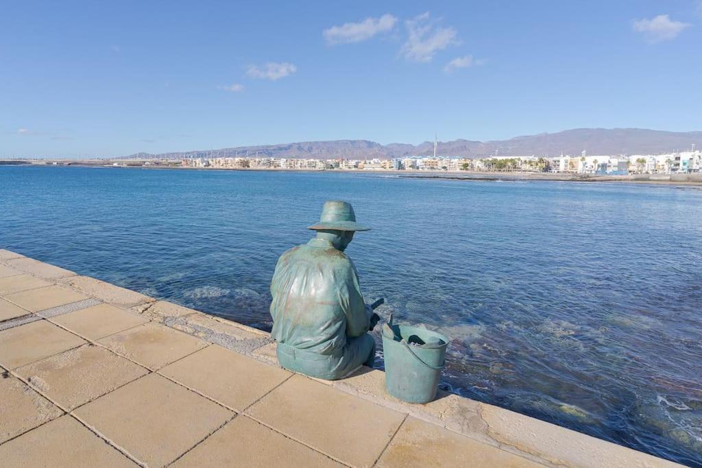 a statue of a man sitting next to the water at Las Afortunadas , Playa Arinaga 1ºA in Arinaga