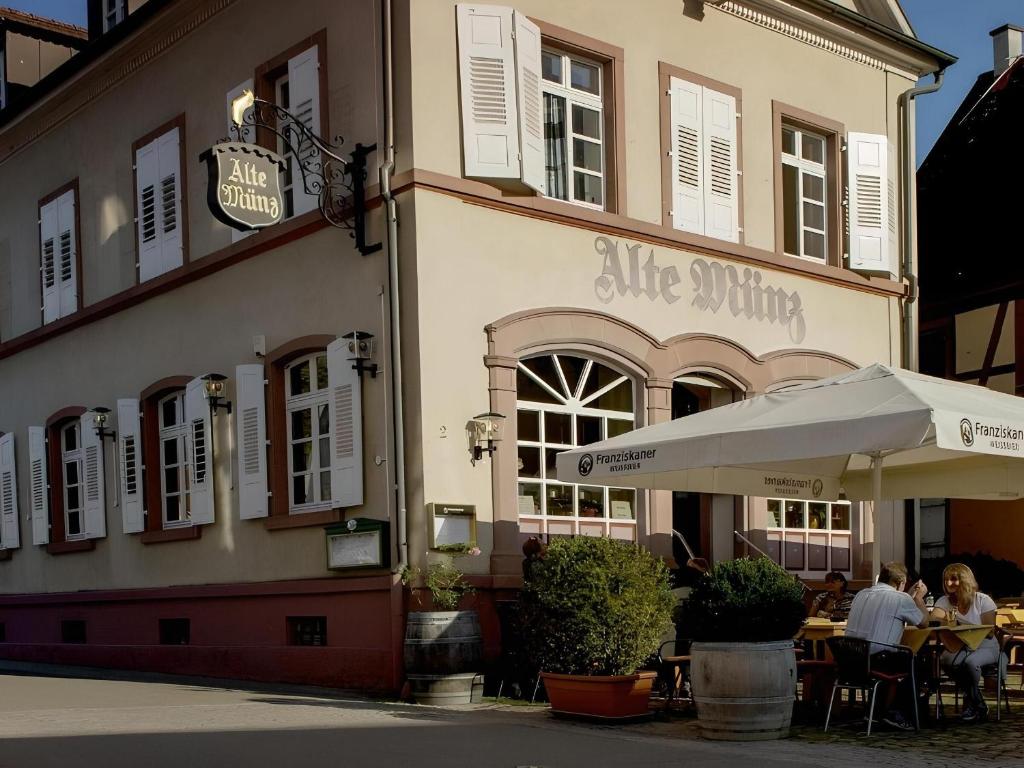 un restaurante con gente sentada en mesas fuera de un edificio en Ferienwohnung Alte Münz, en Müllheim