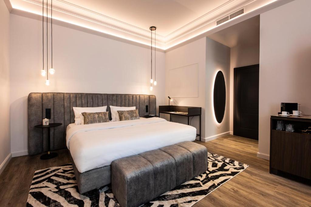 ウィーンにあるO11 Boutique Hotel Viennaのベッドルーム1室(大型ベッド1台、大型オットマン付)