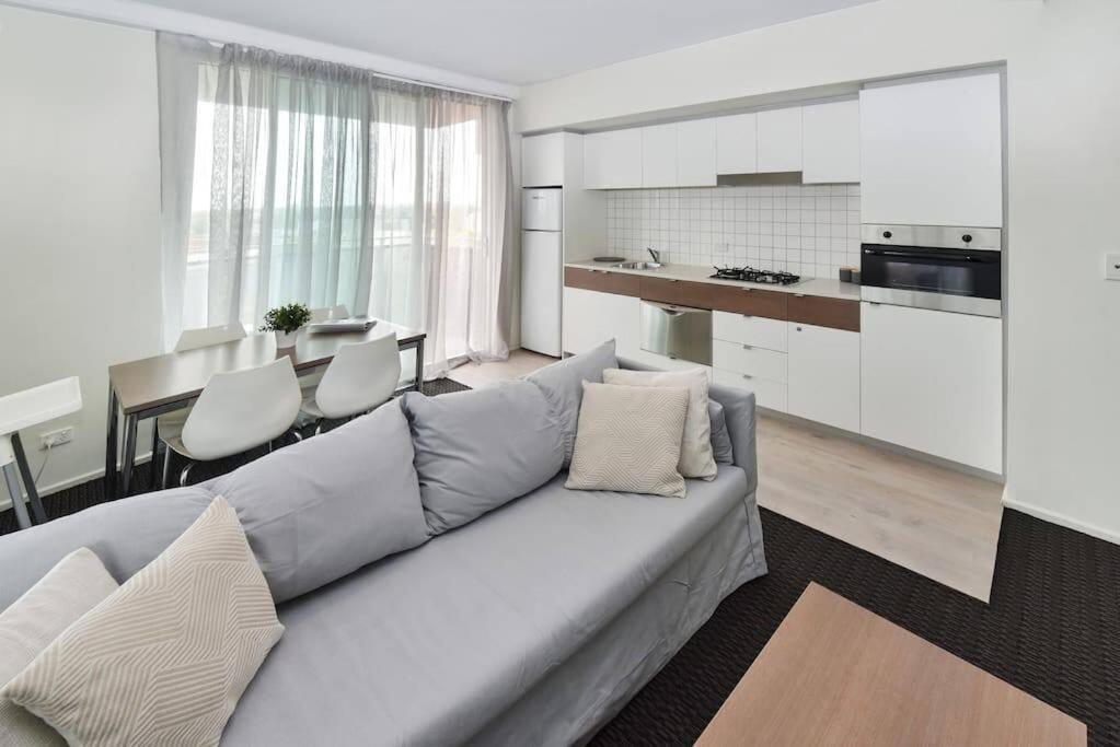 uma sala de estar com um sofá e uma cozinha em Light & Airy 3 Bd CBD Apt: BalconyTramWifi/Parking em Adelaide