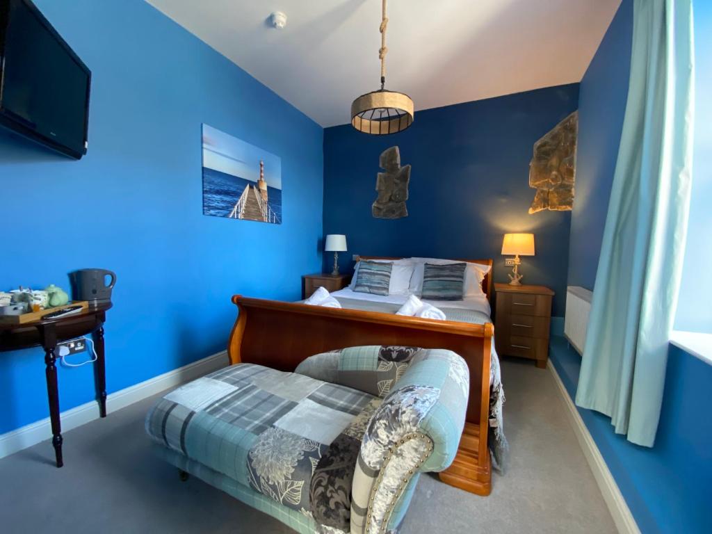 a blue bedroom with a bed and a chair at Harbour Inn in Amble