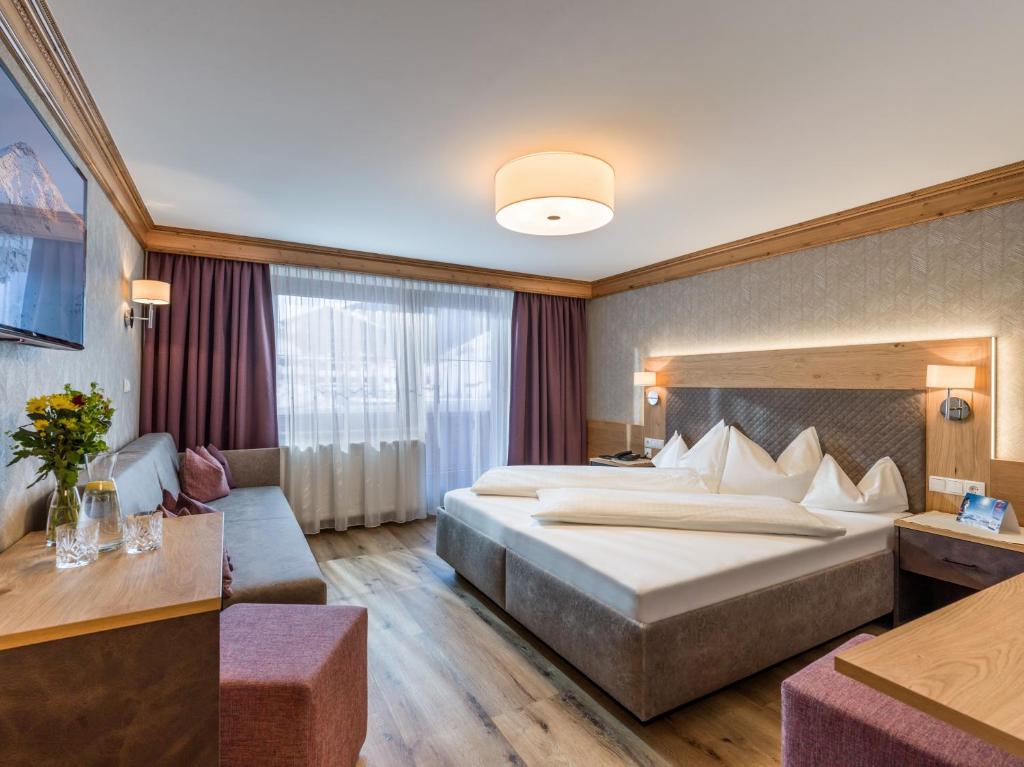 a hotel room with a large bed and a couch at Hotel Kössler in Tux