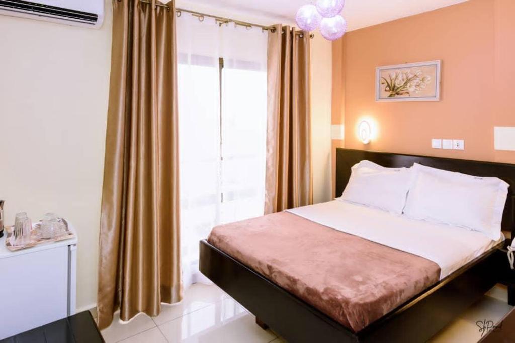 a bedroom with a bed and a large window at Séréna Hôtel in Douala