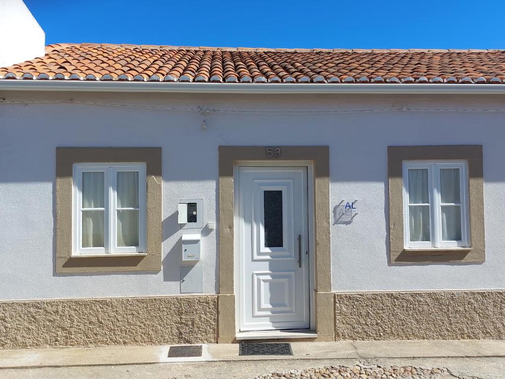 ein weißes Haus mit zwei Fenstern und einer Tür in der Unterkunft Casa do Tio Zé in Golegã