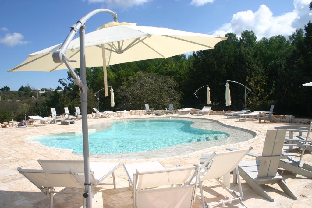 a swimming pool with chairs and an umbrella at Agriturismo Antonelli Piangevino in Monopoli