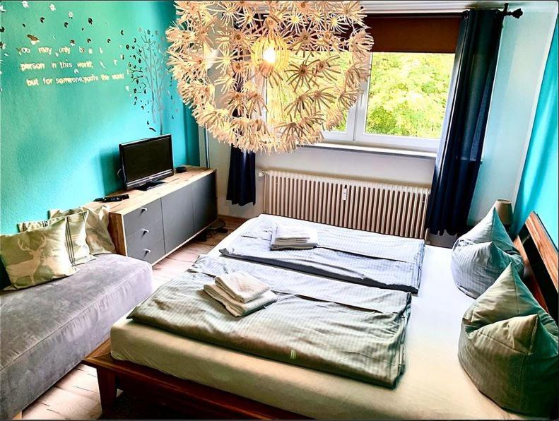 Cette chambre comprend un lit, un canapé et un lustre. dans l'établissement HarzHirsch Bad Sachsa Ferienwohnung, à Bad Sachsa