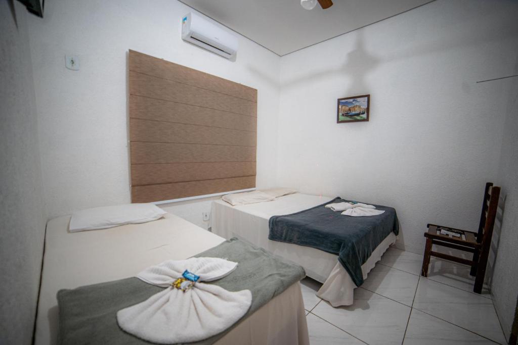 ein Zimmer mit 2 Betten und einem Stuhl darin in der Unterkunft Hotel GranDourados in Dourados
