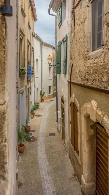 Une ruelle dans une vieille ville avec des bâtiments dans l'établissement Logement cosy au coeur du village, à Peyriac-de-Mer