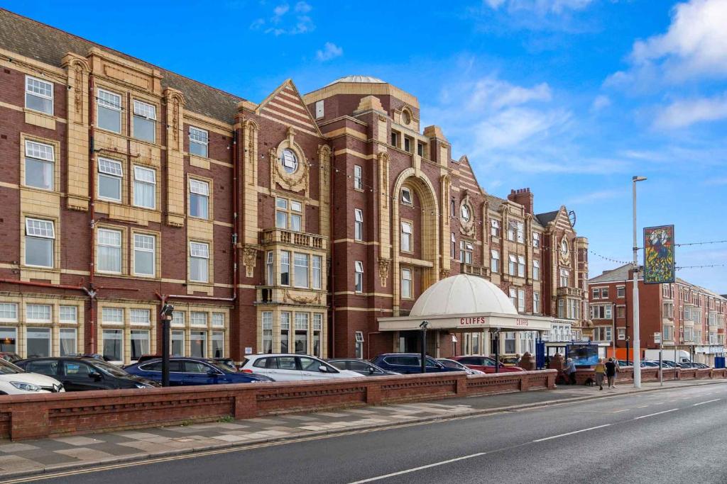 a large brick building with cars parked in front of it at Cliffs Hotel in Blackpool