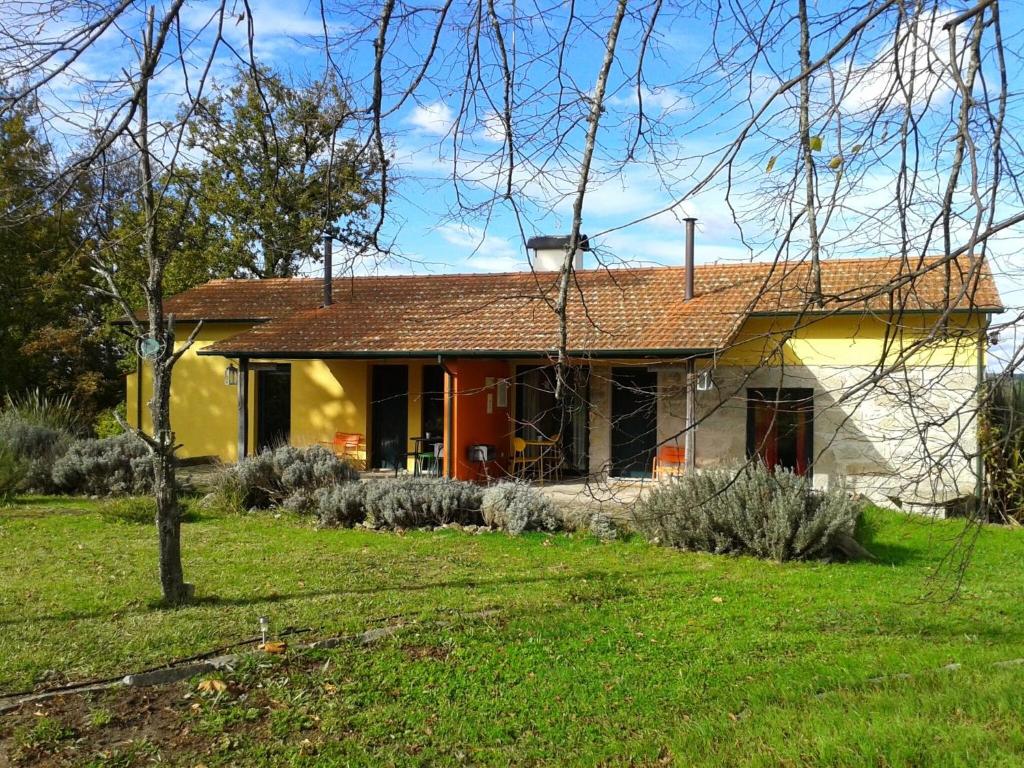 a yellow house with a red roof in a yard at Casa Das Palmeiras-Pedagogic Farm in Mangualde