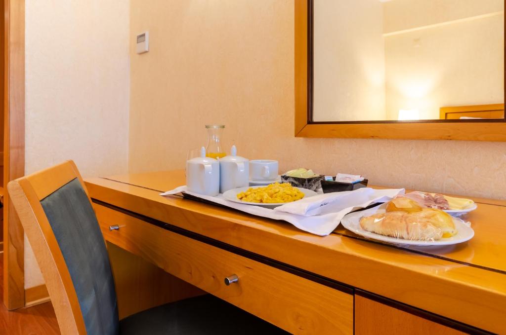 A plated in-room meal with pastries, eggs, fruit, tea and coffee arranged on a wooden sideboard.