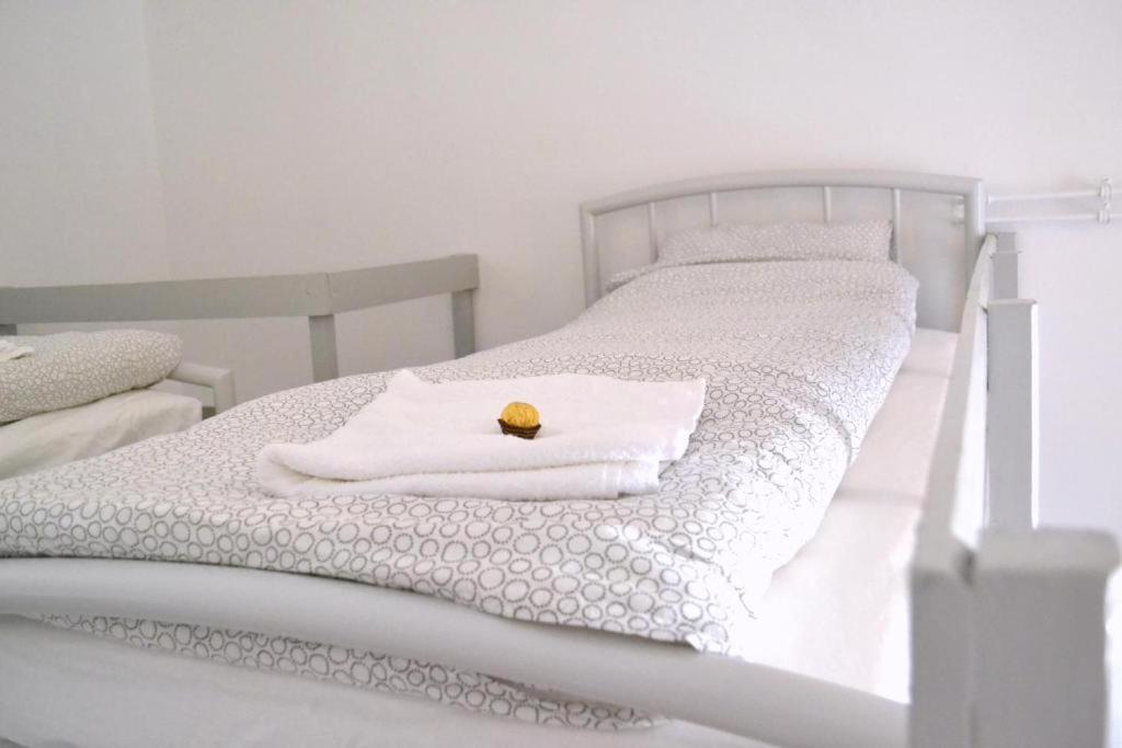 una cama blanca con una manta blanca y un objeto amarillo en ella en BpR Auric Home, en Budapest