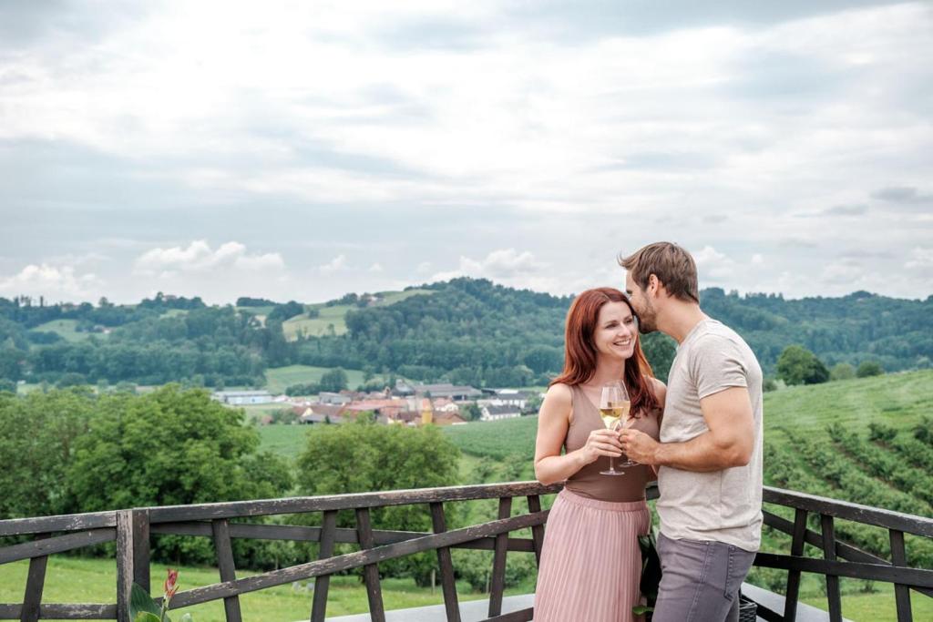 een man en een vrouw die naast een hek staan met een wijnglas bij das MEISTER in Riegersburg