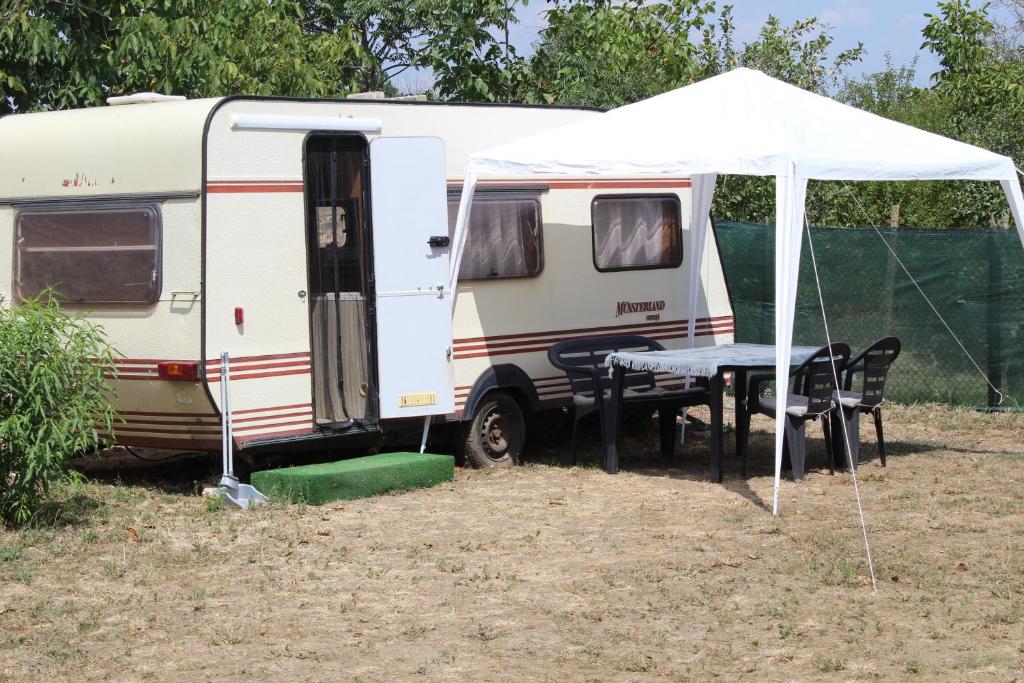 une caravane blanche avec une table et une tente dans l'établissement Kemping pod figą, à Granichar