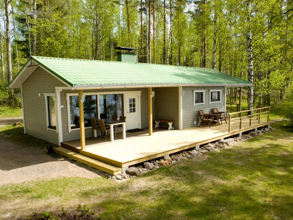 une petite maison avec une terrasse dans les bois dans l'établissement Tiiramökki, à Parikkala