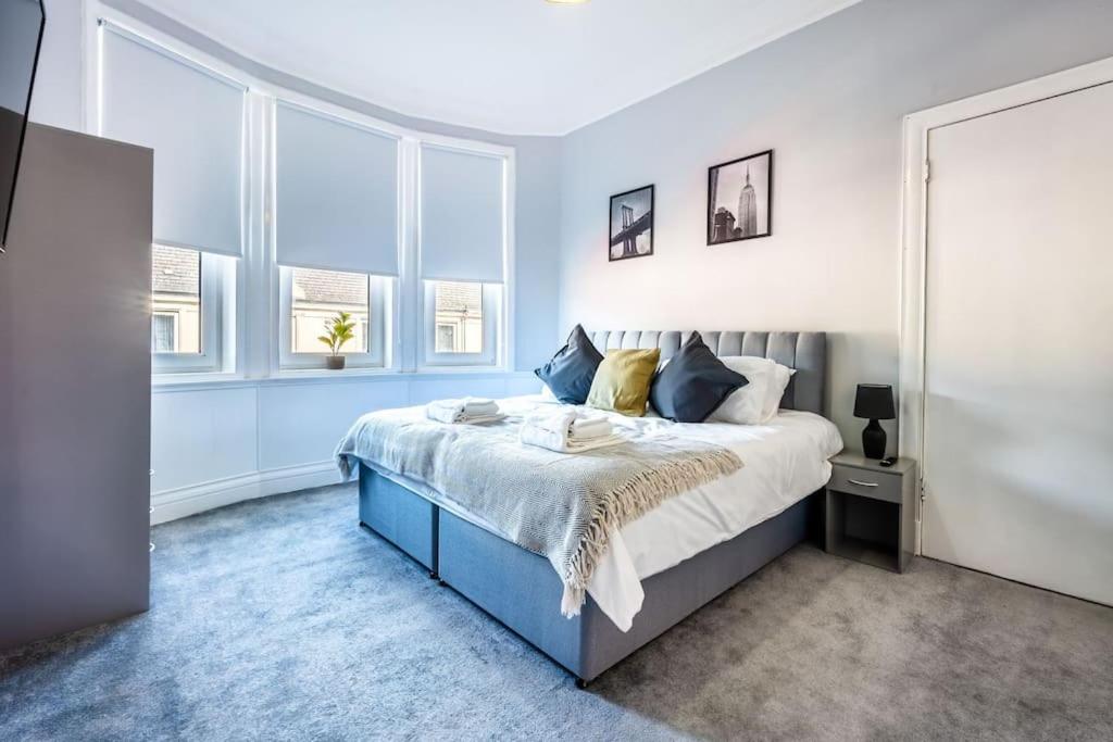 a bedroom with a blue and white bed with windows at Kali Apartment - Spacious 3 bed apartment in Wishaw in Wishaw
