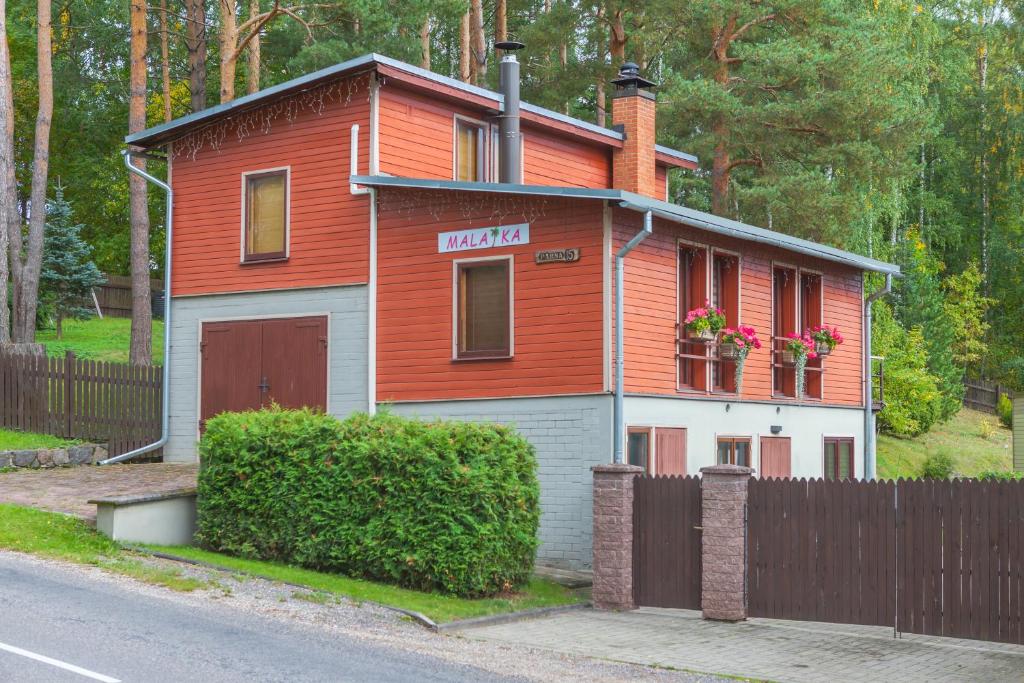 una pequeña casa roja con una valla delante en Külalismaja Malaika, en Põlva