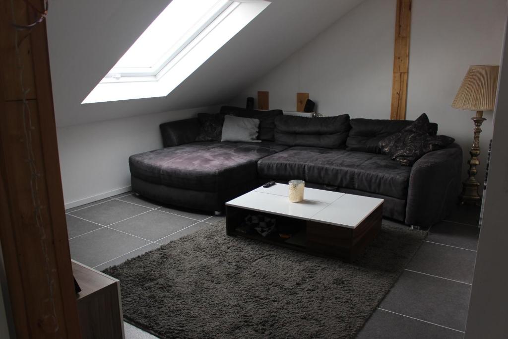ein Wohnzimmer mit einem schwarzen Sofa und einem Tisch in der Unterkunft ALB-Wohnung - Schwäbische Alb in Heroldstatt