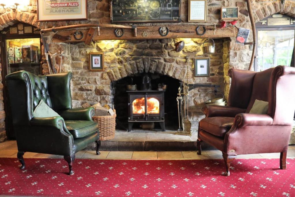 a living room with chairs and a stone fireplace at The Countryman’s Inn in Hunton