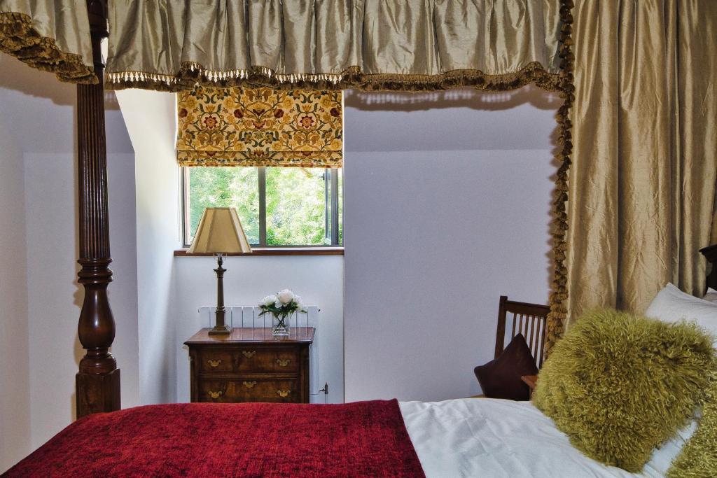 um quarto com uma cama de dossel e uma janela em The Loft at Hewletts Farm - Stunning Apartment on The Cotswold Way Close to Cheltenham em Cheltenham