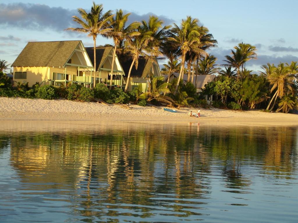 ein Haus am Strand mit Palmen und Wasser in der Unterkunft Whitesands Beach Villas in Rarotonga