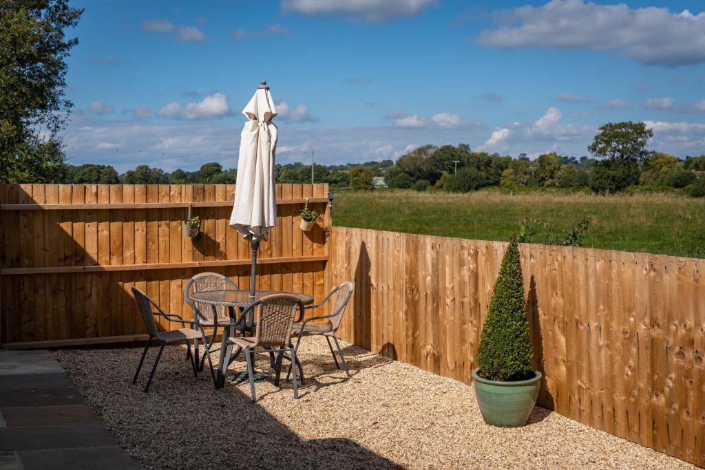 a patio with a table and an umbrella and a fence at Finest Retreats - Rosebud Cottage in Wedmore