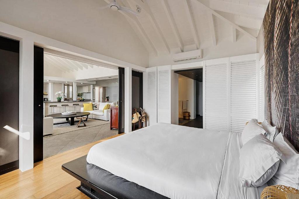 a bedroom with a white bed and a living room at Infiniti Entire Luxury Villa Breath Taking View in St Barth in Pointe Milou