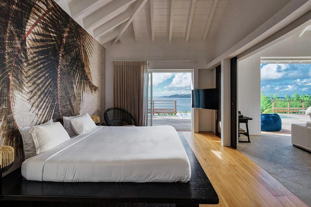 a bedroom with a large bed and a view of the ocean at Infiniti Entire Luxury Villa Breath Taking View in St Barth in Pointe Milou
