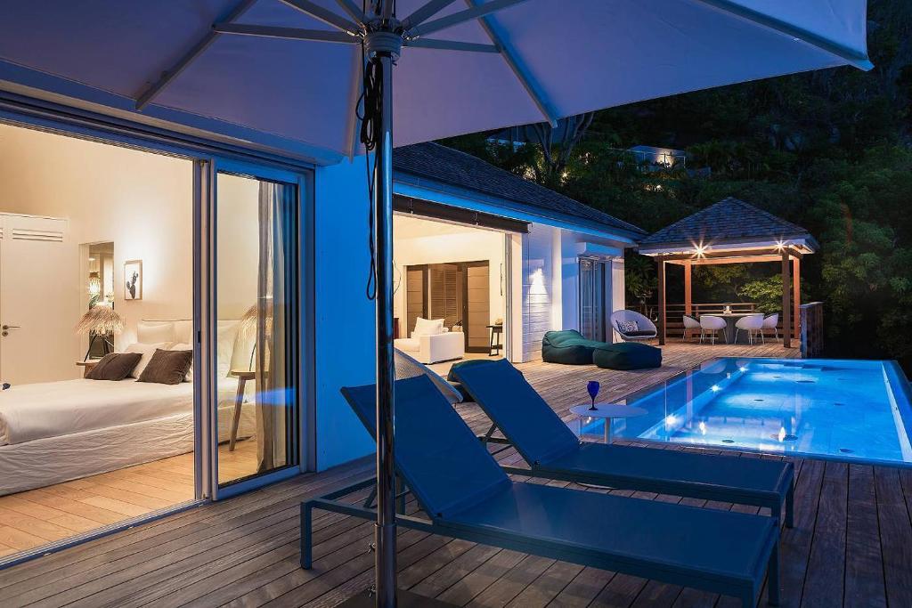 a house with a swimming pool and an umbrella at Infiniti Entire Luxury Villa Breath Taking View in St Barth in Pointe Milou