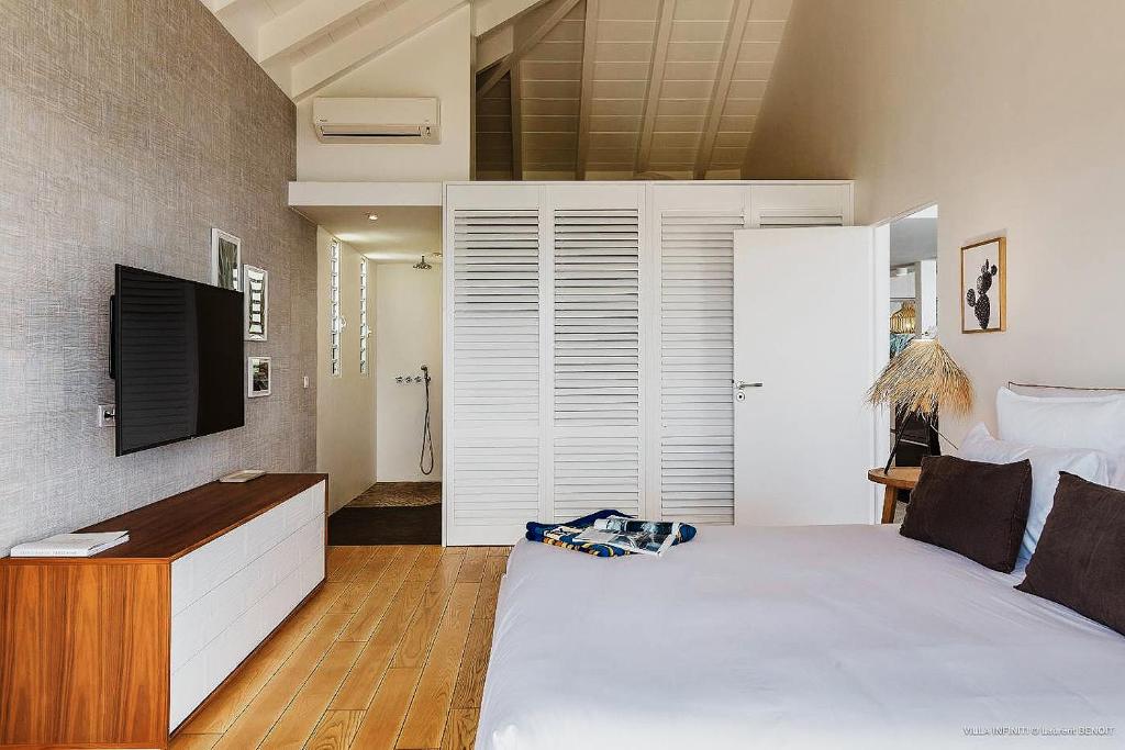 a bedroom with a large white bed and a television at Infiniti Entire Luxury Villa Breath Taking View in St Barth in Pointe Milou