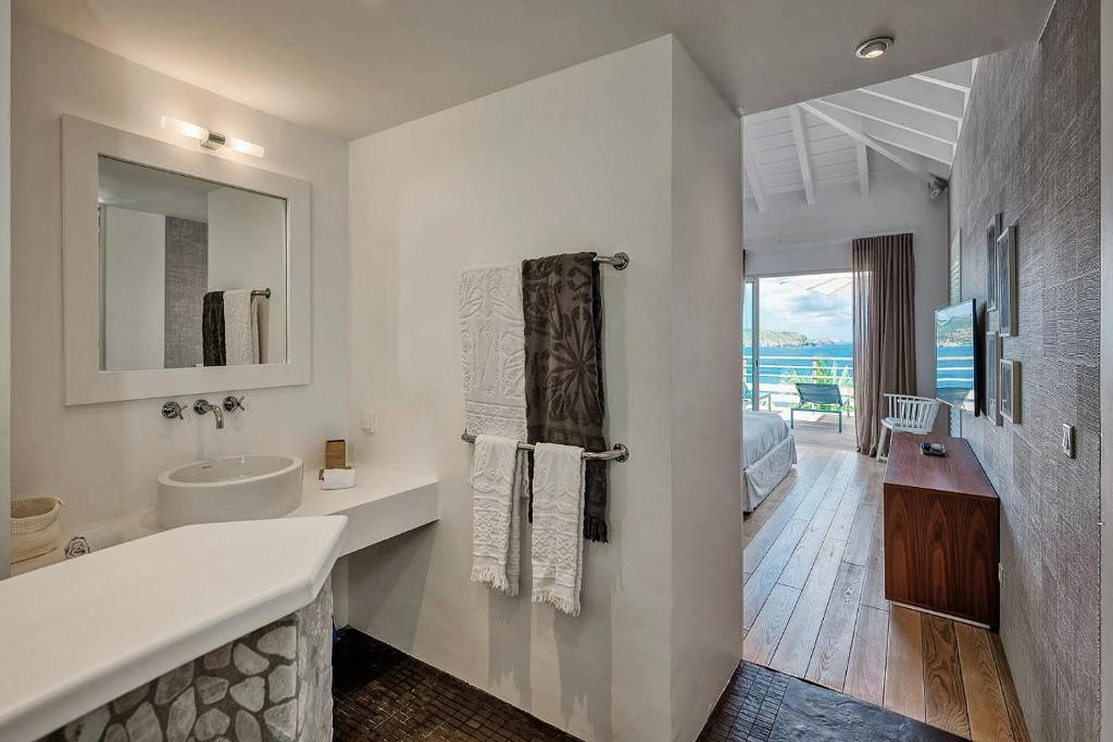 a white bathroom with a sink and a mirror at Infiniti Entire Luxury Villa Breath Taking View in St Barth in Pointe Milou