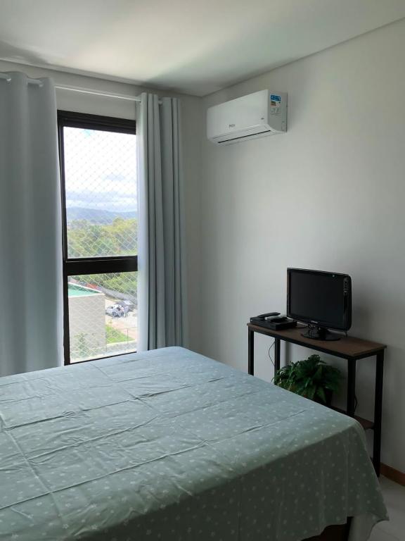 a bedroom with a bed and a television and a window at Itacolomi Home Club Apto 404 T1 in Penha