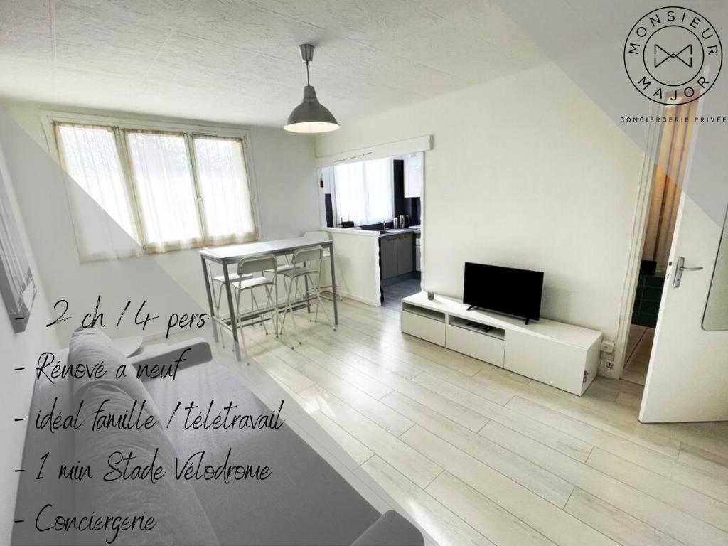 ein weißes Wohnzimmer mit einem Tisch und einem TV in der Unterkunft Charmant Appart Stade Vélodrome/Métro Centre Ville in Marseille