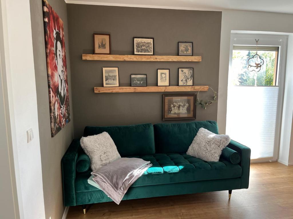 a green couch in a living room with shelves at Schiller Apartment in Münchberg