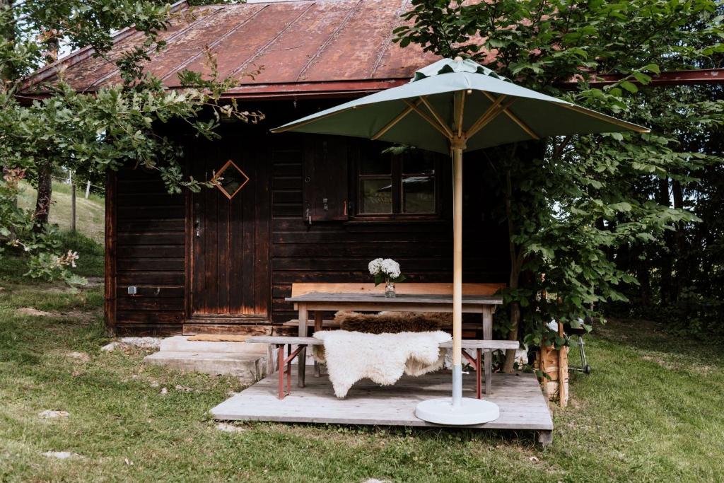 - une table de pique-nique avec un parasol en face d'une cabine dans l'établissement Haslauer Hüttn, à Frasdorf