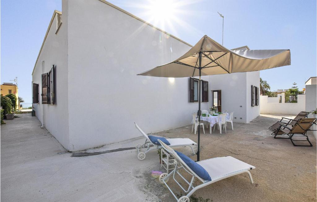 un patio con sillas, una sombrilla y una mesa en Lovely Home In Triscina With Wifi, en Triscina