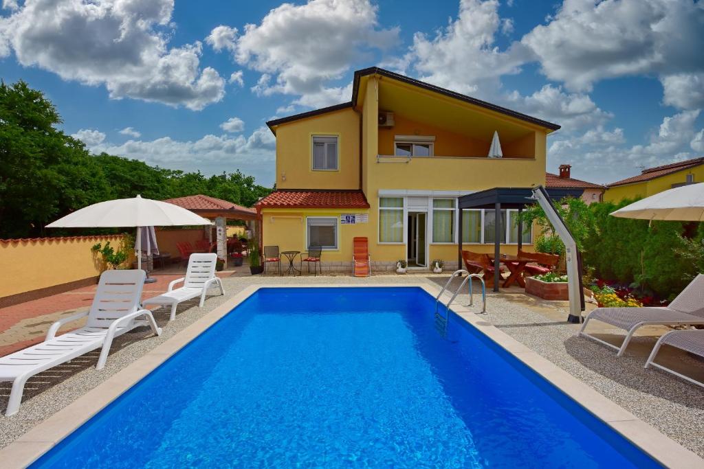 a villa with a swimming pool and a house at APP Laura with Common Pool in Nova Vas
