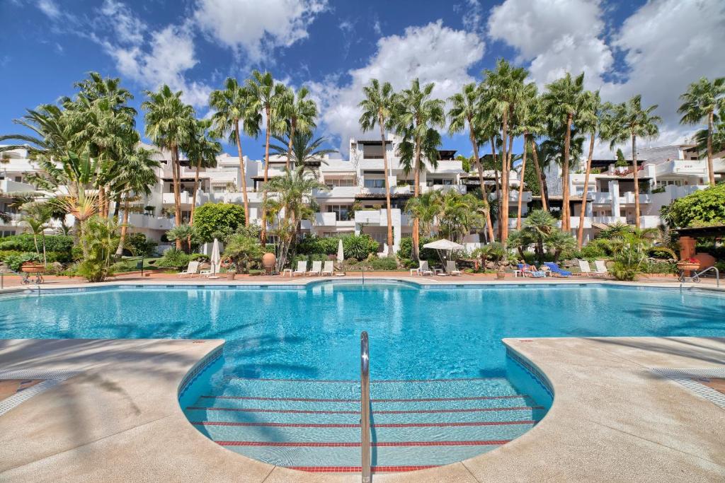 una piscina con palmeras y edificios en BRIGHT NEW APARTMENT IN PUENTE ROMANO en Marbella