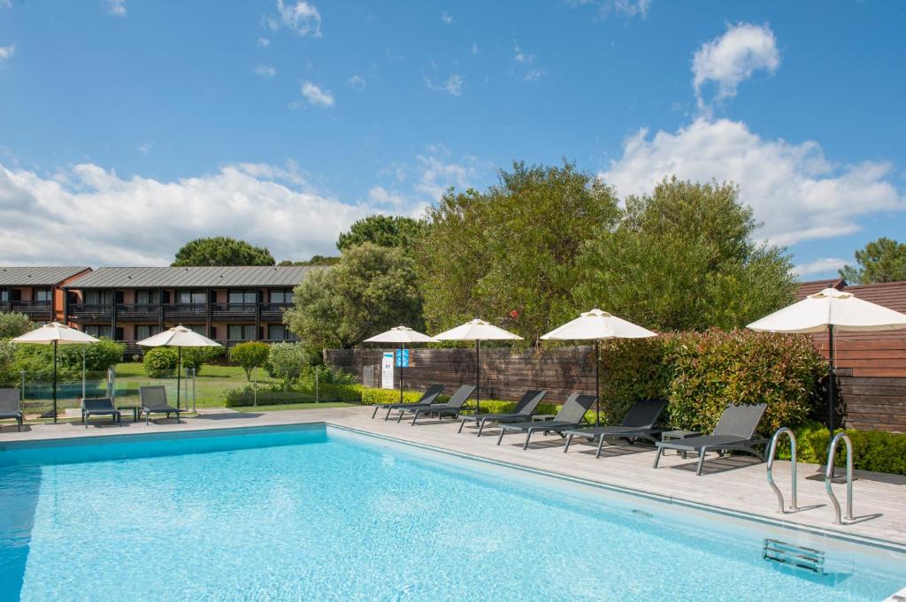 a swimming pool with chairs and umbrellas at Hôtel Castell'Verde in Porto-Vecchio