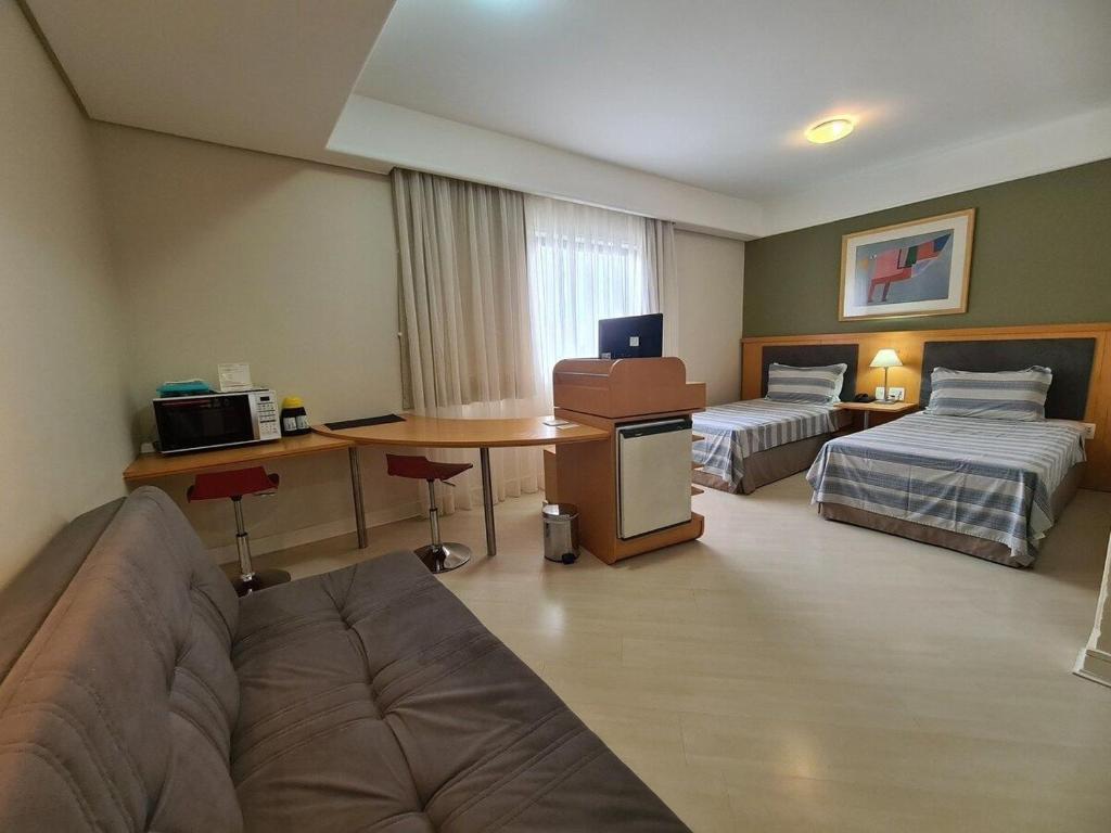 a hotel room with two beds and a desk at Bienal First Class Flat Service - UH607 in São Paulo