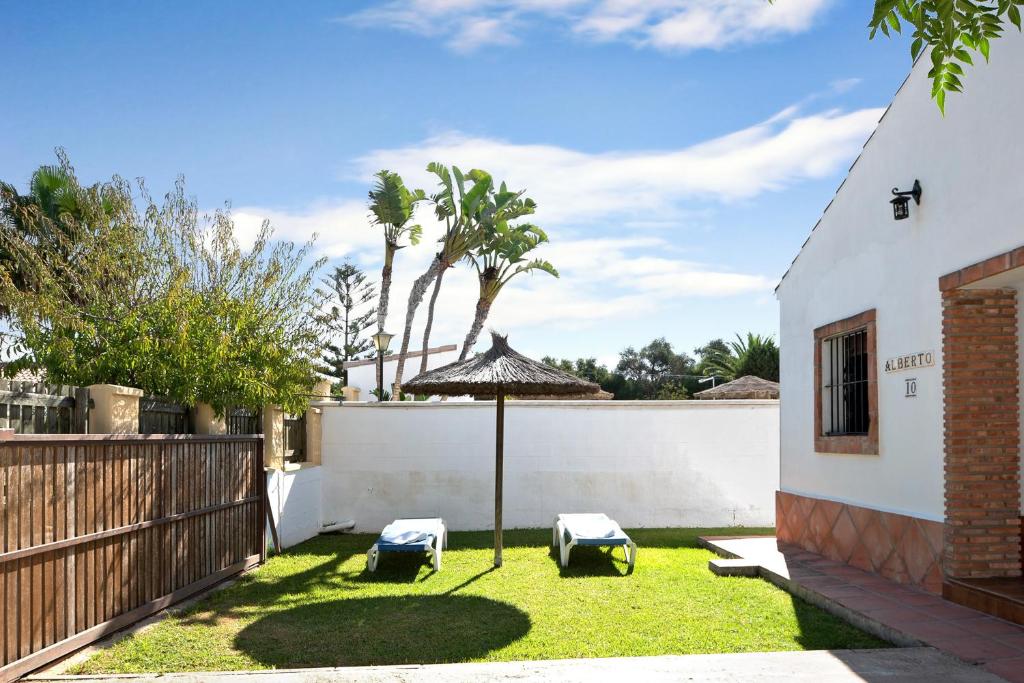 a yard with two chairs and an umbrella at Casa Alberto in Zahora