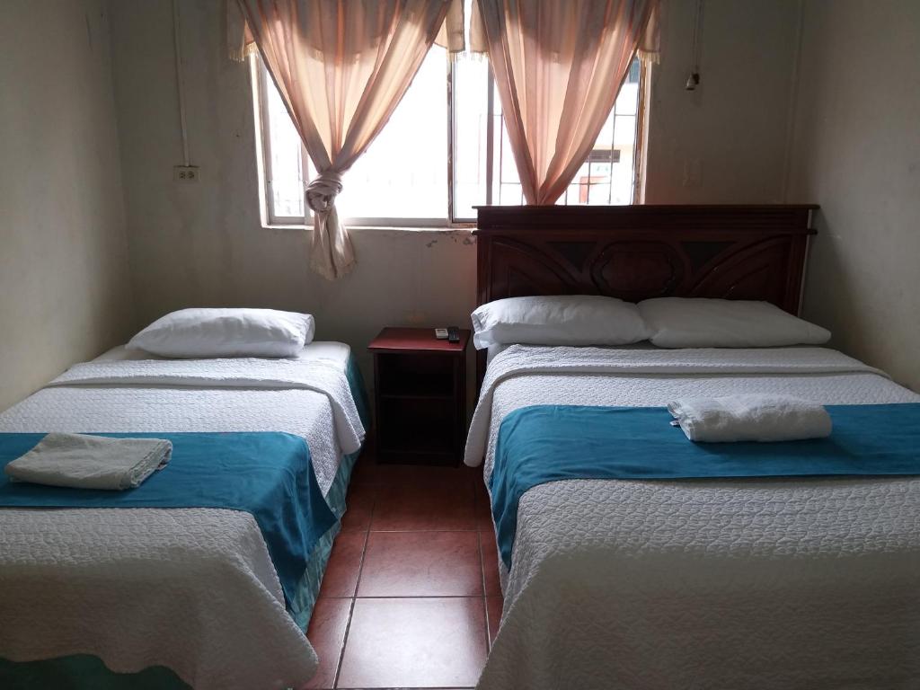 two beds in a room with a window at Hostal Miconia in Puerto Ayora