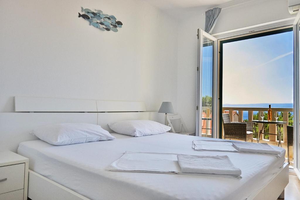 a white bedroom with a bed with a view of the ocean at Guest House Marija in Bol
