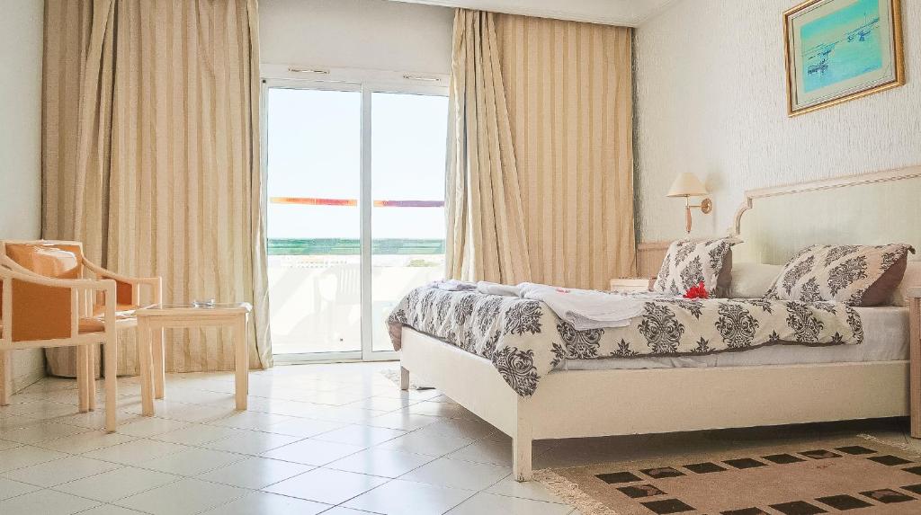 1 dormitorio con cama y ventana grande en Hotel Royal Jinene Sousse, en Sousse