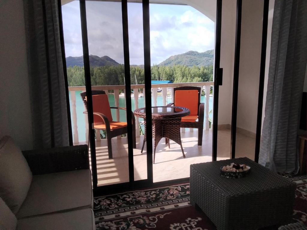 uma sala de estar com uma varanda com uma mesa e cadeiras em Belle Rose Vue guest house em Baie Sainte Anne