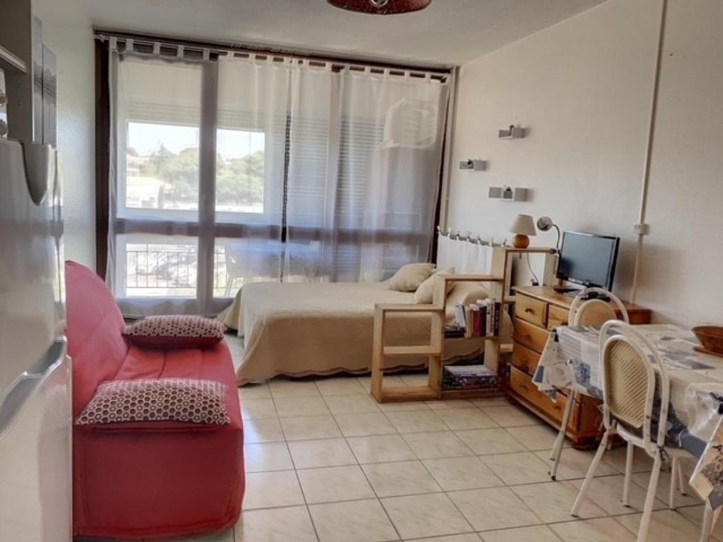 une chambre avec un lit et une télévision dans une pièce dans l'établissement Appartement cosy avec balcon, proche des Thermes, animaux admis, climatisation et Wifi inclus - FR-1-503-128, à Balaruc-les-Bains
