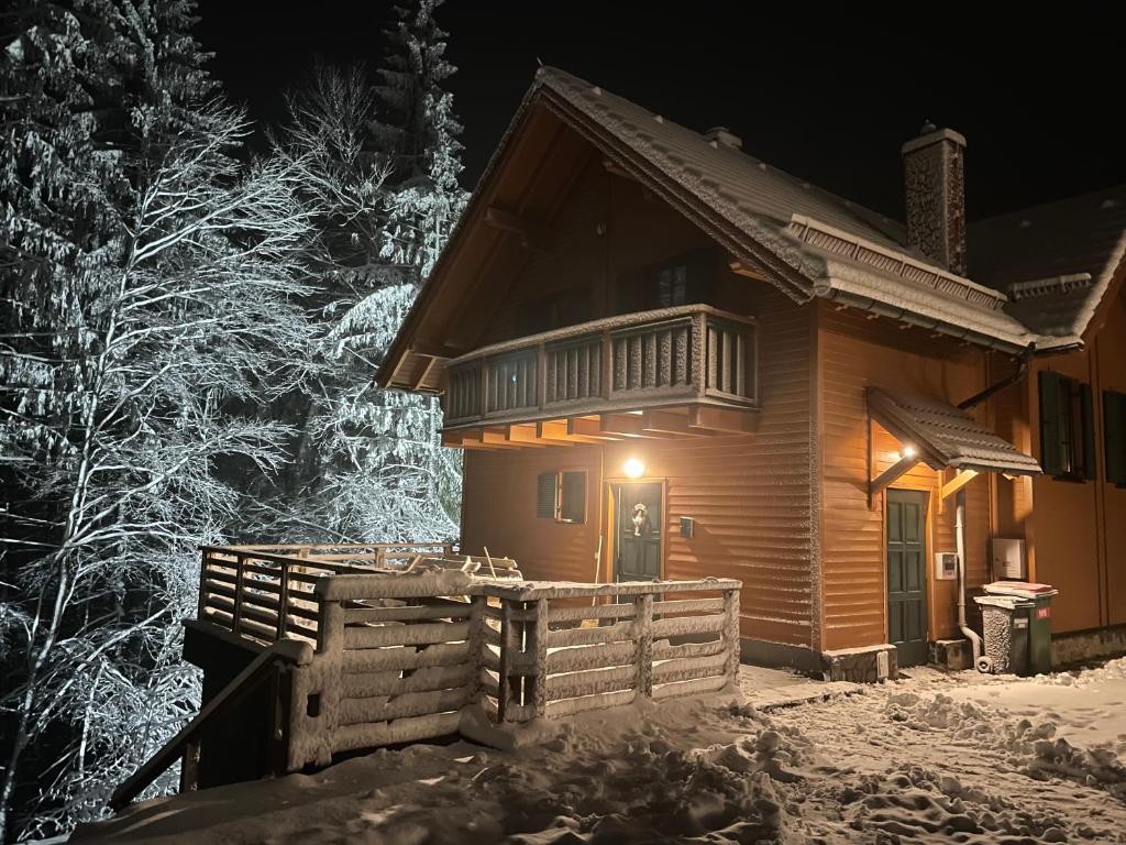 una cabaña de madera en la nieve por la noche en Chalet ANRA Pohorje en Zgornje Hoče